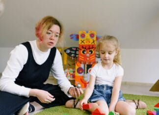 Kobieta i dziecko bawią się kolorowymi klockami w sali zabaw