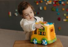 Małe dziecko bawi się kolorową ciężarówką w domu