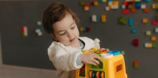 Małe dziecko bawi się kolorową ciężarówką w domu