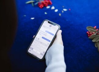 Osoba trzymająca smartfon z wiadomościami tekstowymi na niebieskim tle z kwiatam